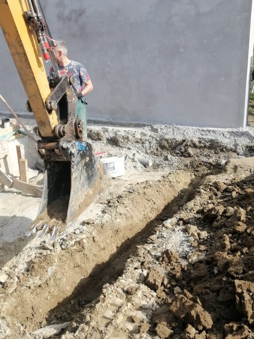 Postavljanje kanalizacionih cevi uz kuću tokom mašinskog iskopa rova
