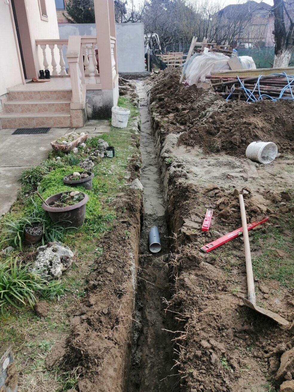 Postavljanje kanalizacione cevi u iskopanom rovu pored porodične kuće