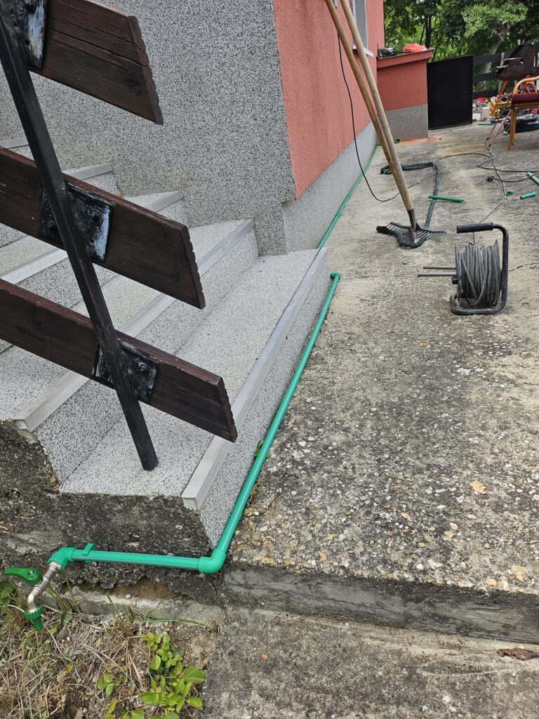 Postavljanje vodovodnih cevi za česmu duž spoljne staze pored kuće